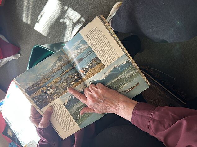 a hand pointing at a picture in an open magazine